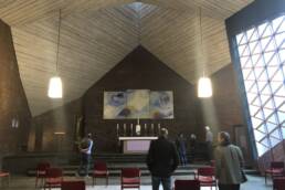 Innenraum einer Kirche der Anthroposophischen Christengemeinschaft mit schlichter Architektur, Altar und Besuchern, die Besinnung und Gemeinschaft erleben.